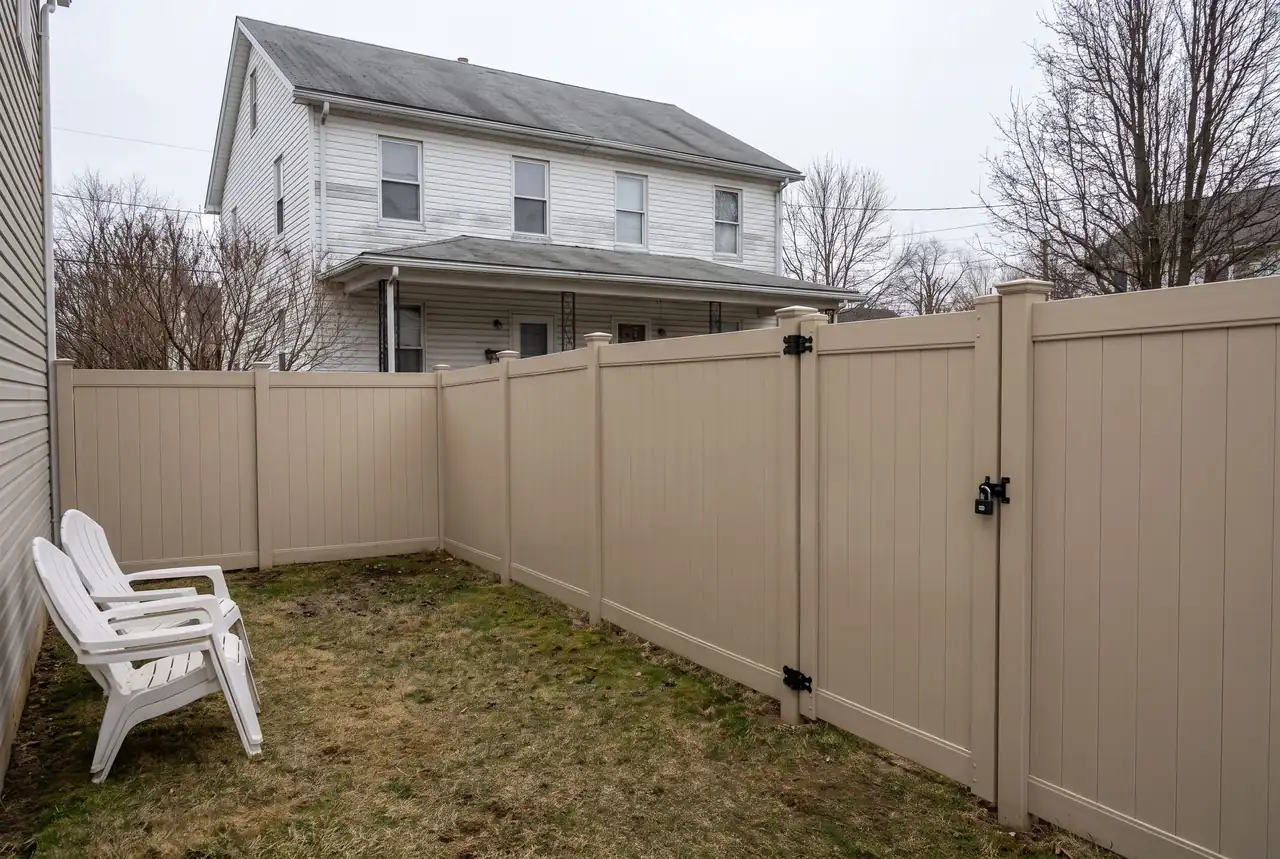 Duplex rental with a tan vinyl privacy fence and a locking gate